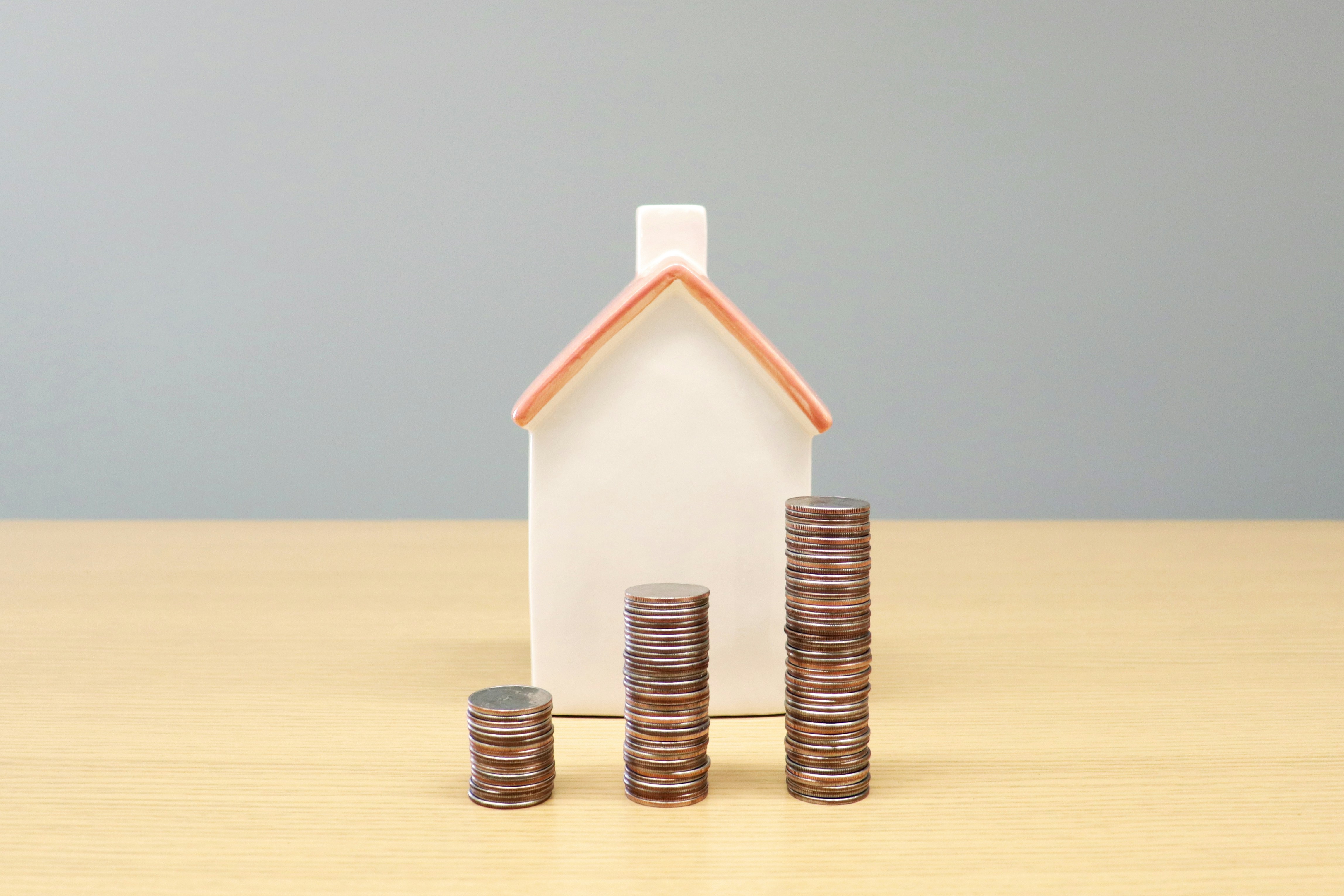 Small ceramic house model with stacked coins representing conventional loan down payment options