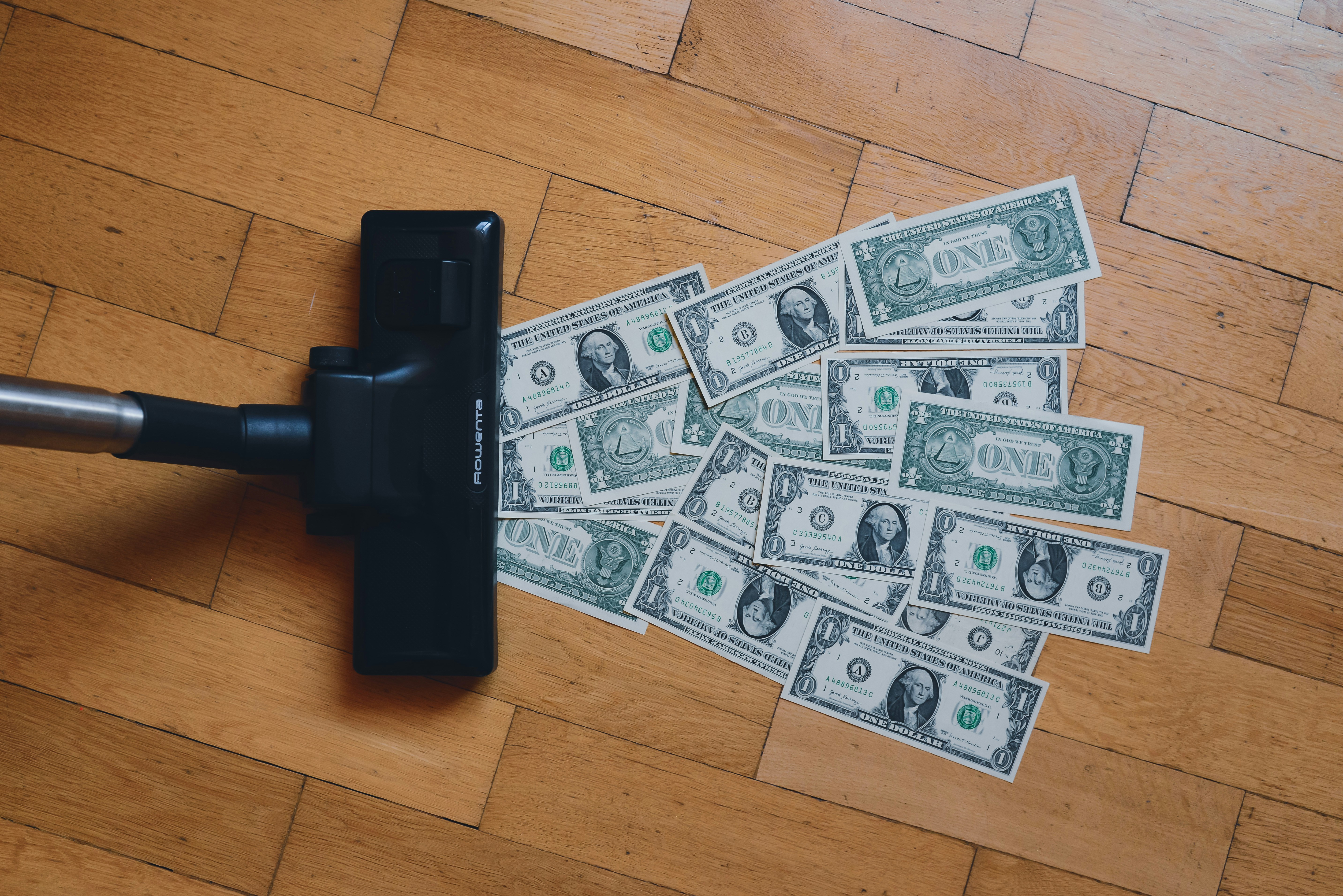 Vacuum cleaner sweeping up dollar bills — stop losing money to the 20% down payment myth
