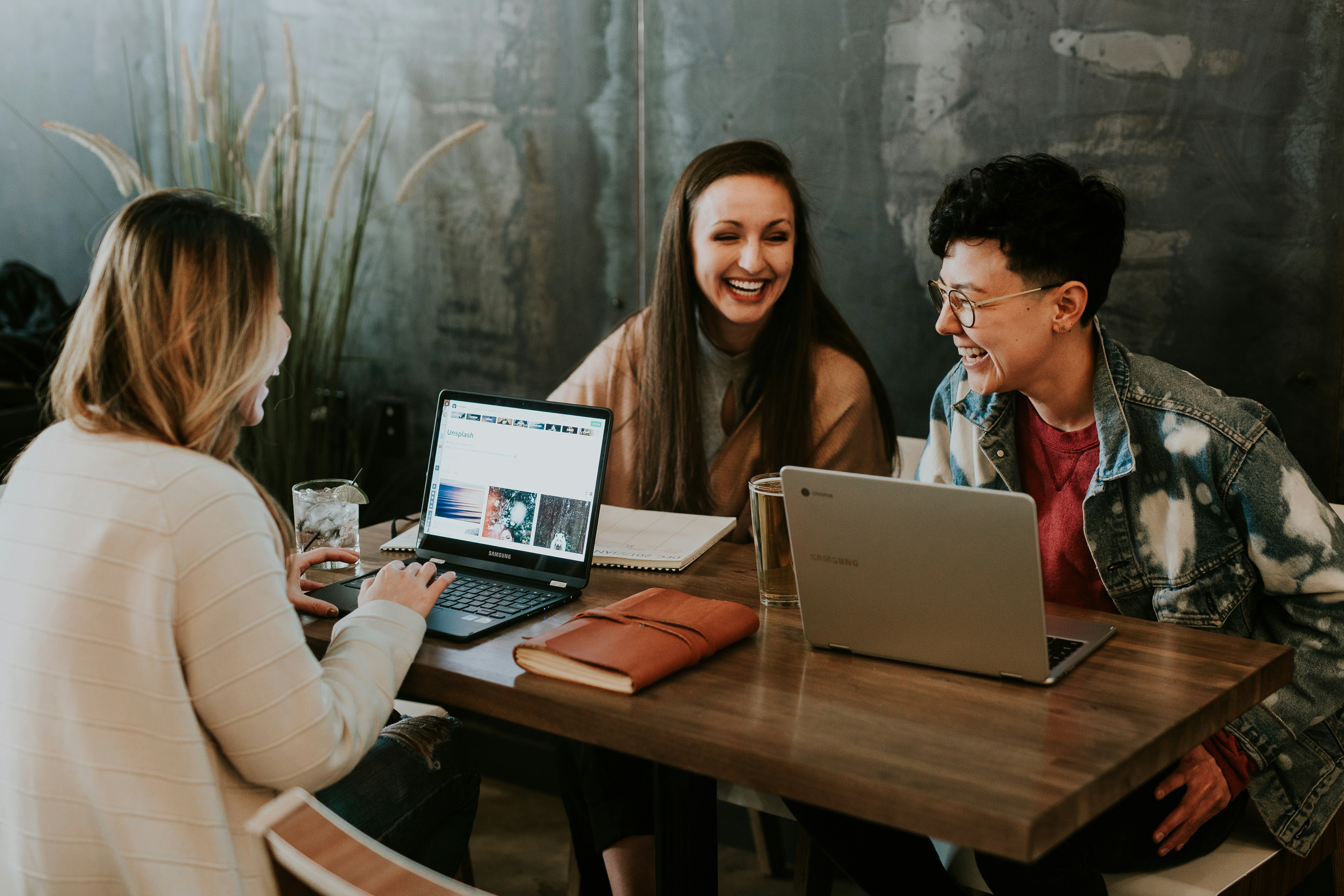 Three people meeting and laughing around a table with laptops — mortgage consultation